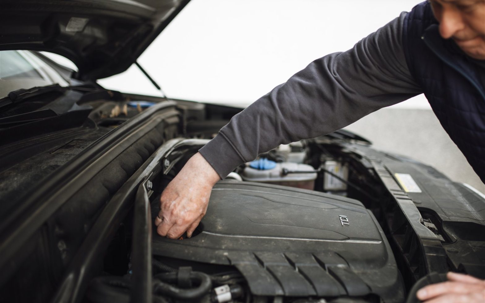 Mecânico revisando o motor de um carro com o capô aberto