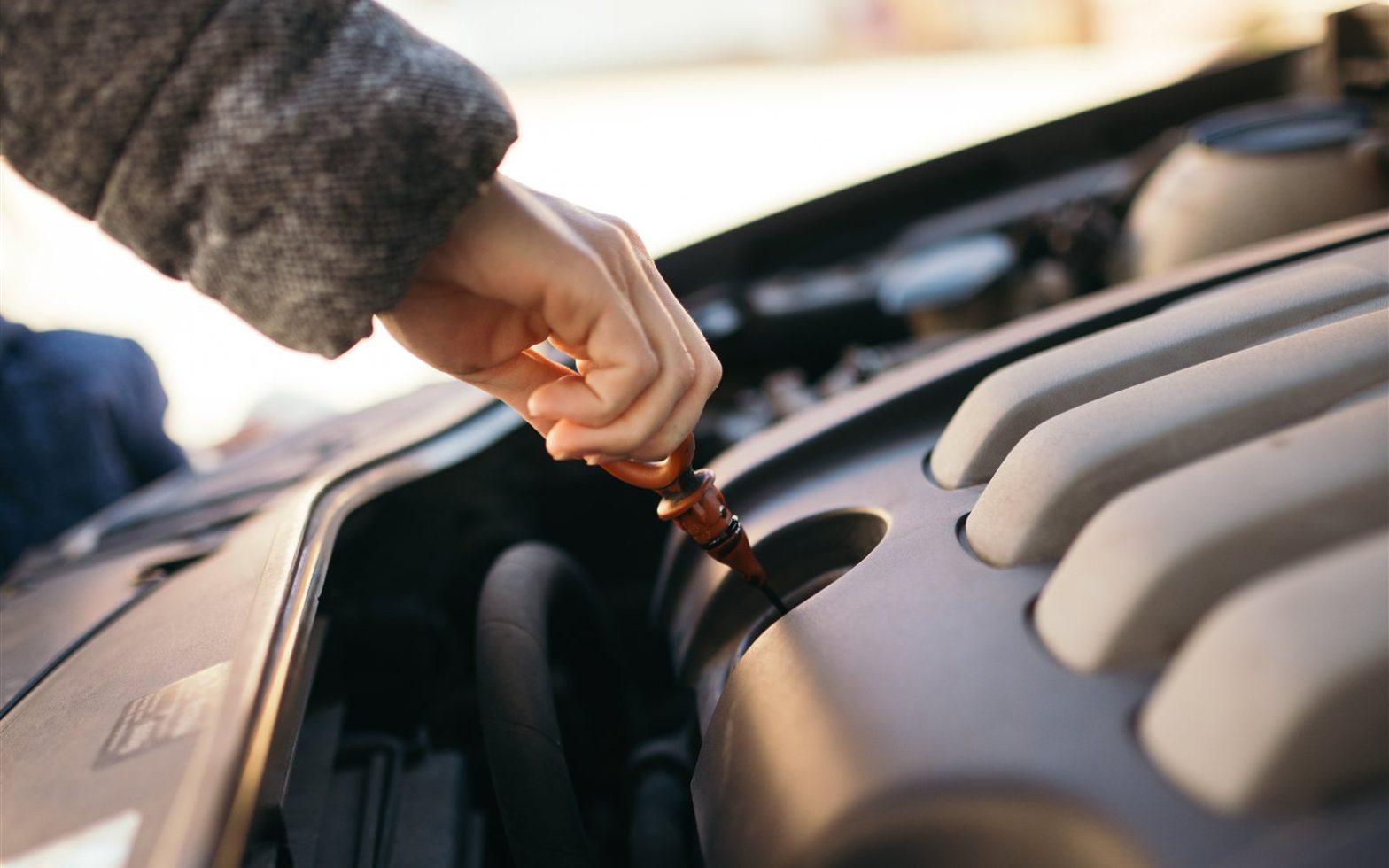 Pessoa verificando o nível de óleo do motor com a vareta medidora